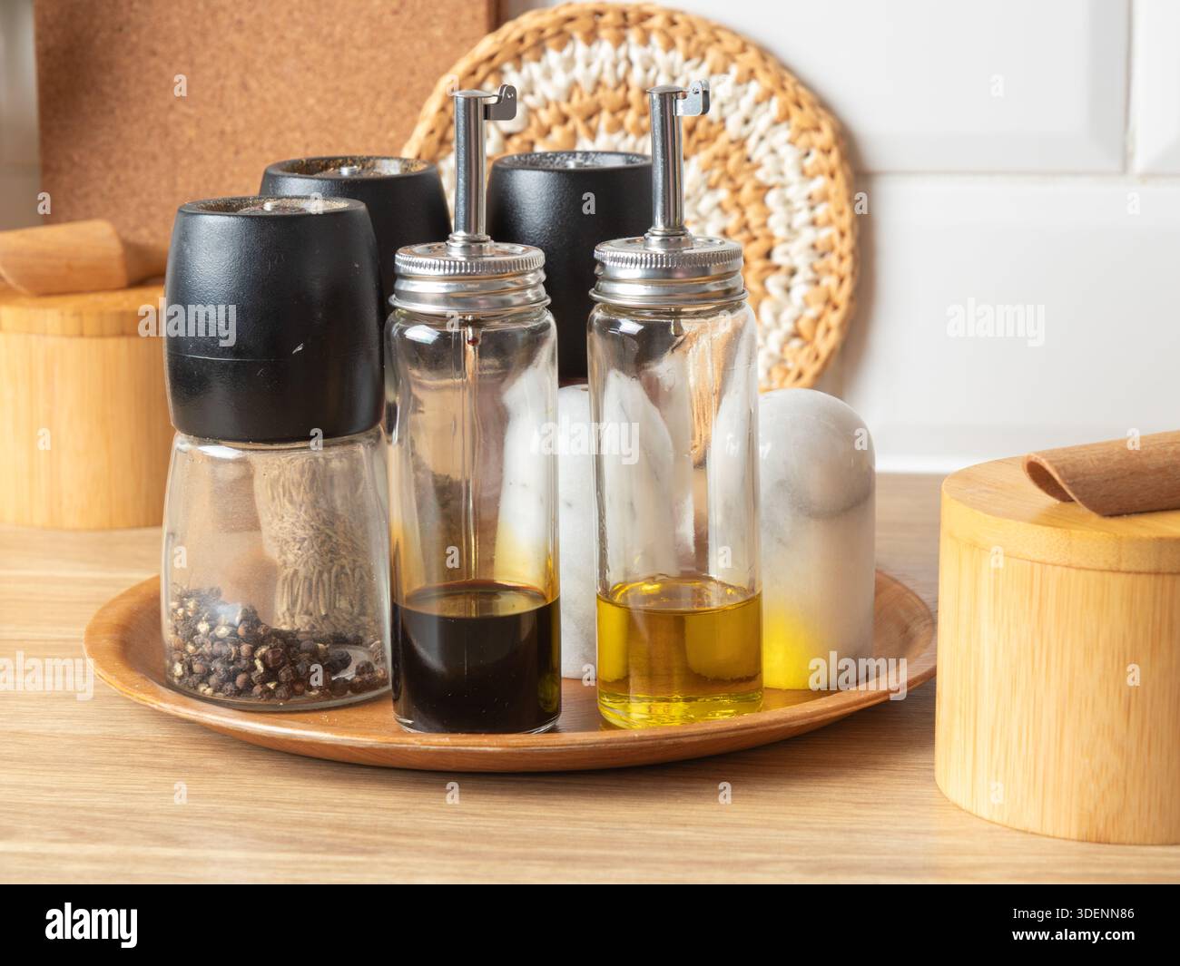 Un vassoio rotondo in bambù contiene una serie di macine di sale e pepe, una crosta di olio e aceto e un contenitore per stuzzicadenti, creando una linguetta ordinata ed elegante Foto Stock