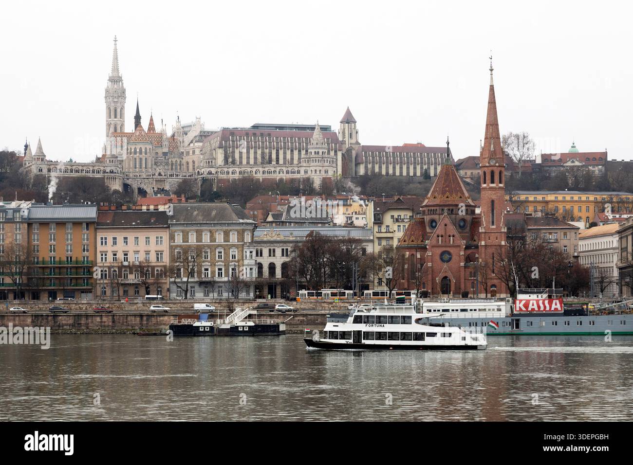Una barca sul Danubio a Budapest, Ungheria, in inverno. La collina del castello (Várhegy) sorge sopra il corso d'acqua sul lato Buda della città. Foto Stock