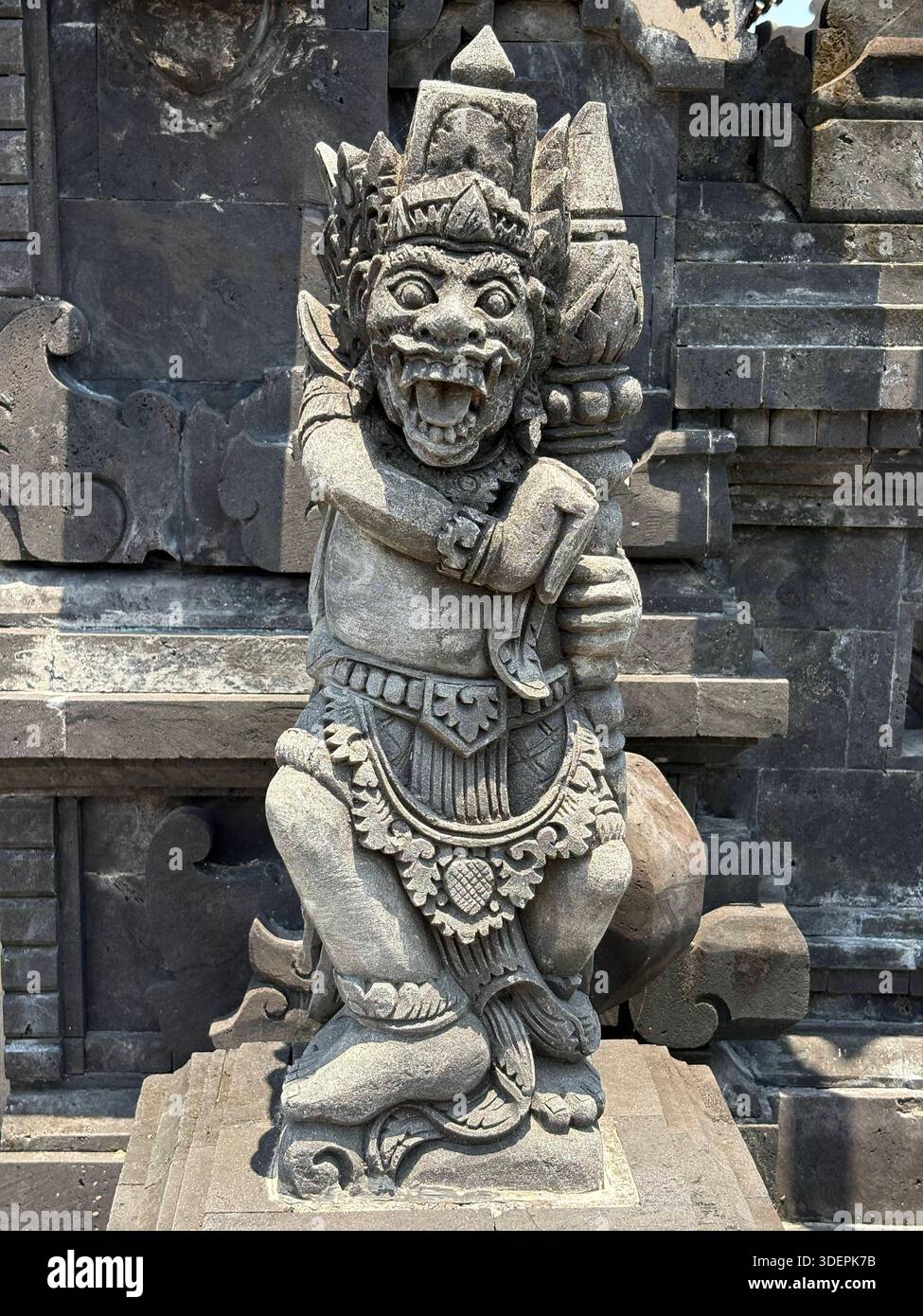 Statua in pietra intagliata in modo intricato di una mitologica figura guardiana di fronte al tempio di Bali, Indonesia - Immagine stock catturata con smartphone