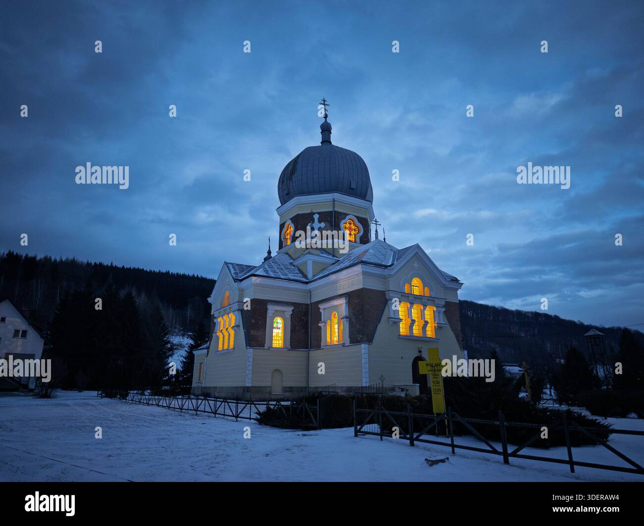 Chiesa ortodossa a Polany vicino a Krempna al crepuscolo, Low Beskids, Polonia. Luce calda che si illumina dalle finestre di una chiesa contro un cielo notturno blu profondo. Foto Stock