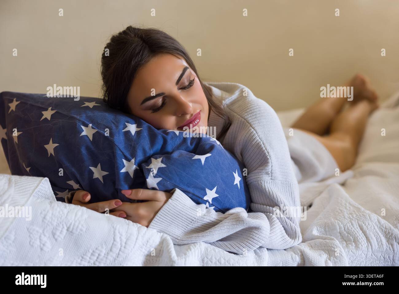 Bella giovane donna che indossa un maglione bianco chunky rilassante a letto Foto Stock