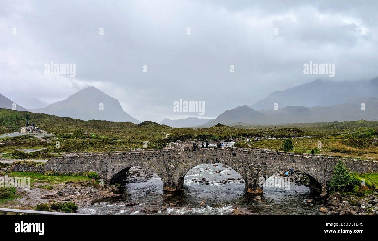 Lo storico ponte in pietra di Sligachan sull'isola di Skye durante una classica giornata delle Highland piovose, avvolto da nebbia, montagne e dall'atmosfera scozzese Foto Stock