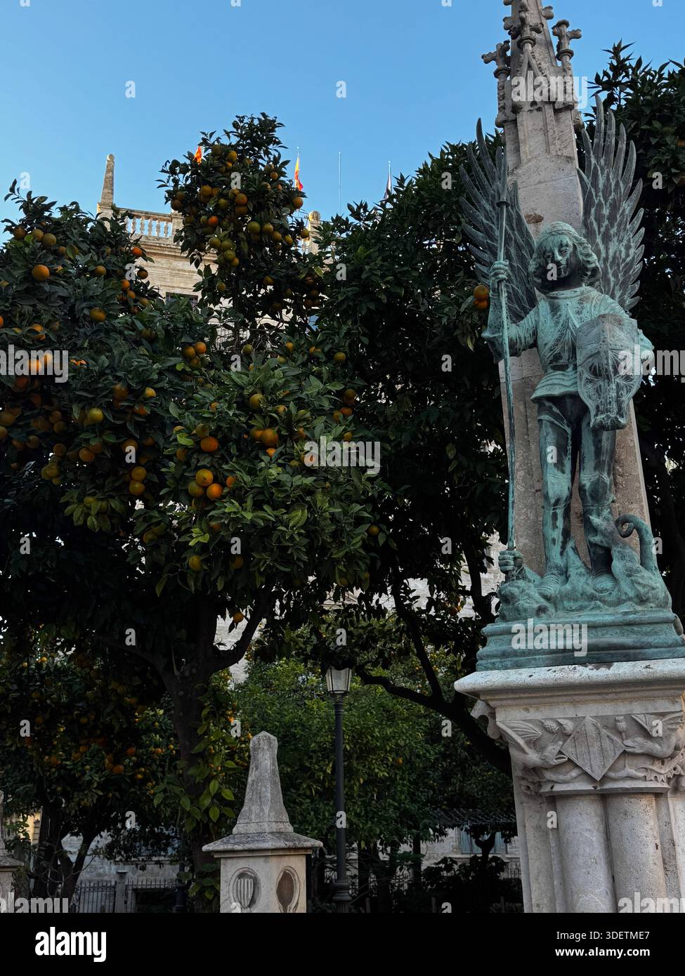 Monumento in marmo circondato da alberi verdi e arance mature in un giardino pubblico di Valencia, Spagna. Foto Stock