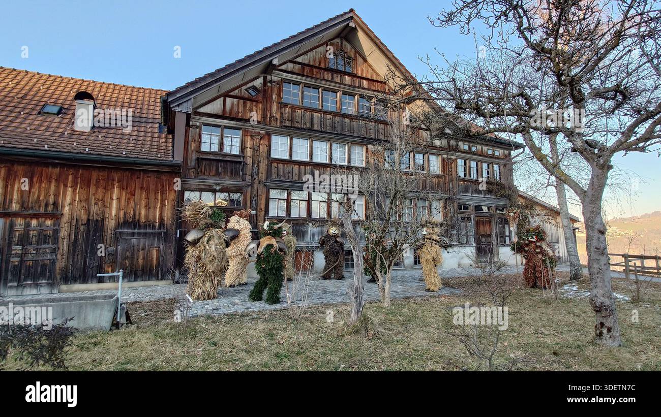 31 dicembre 2025, Stein, Svizzera: Artisti tradizionali di Silvesterchlausen in costumi e maschere ornati in una storica fattoria a graticcio Foto Stock