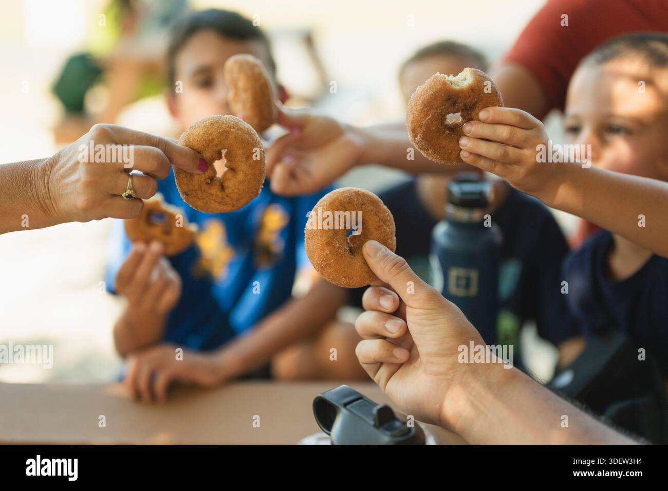 Gruppo di bambini che tostano ciambelle al sidro di mele al tavolo da picnic Foto Stock