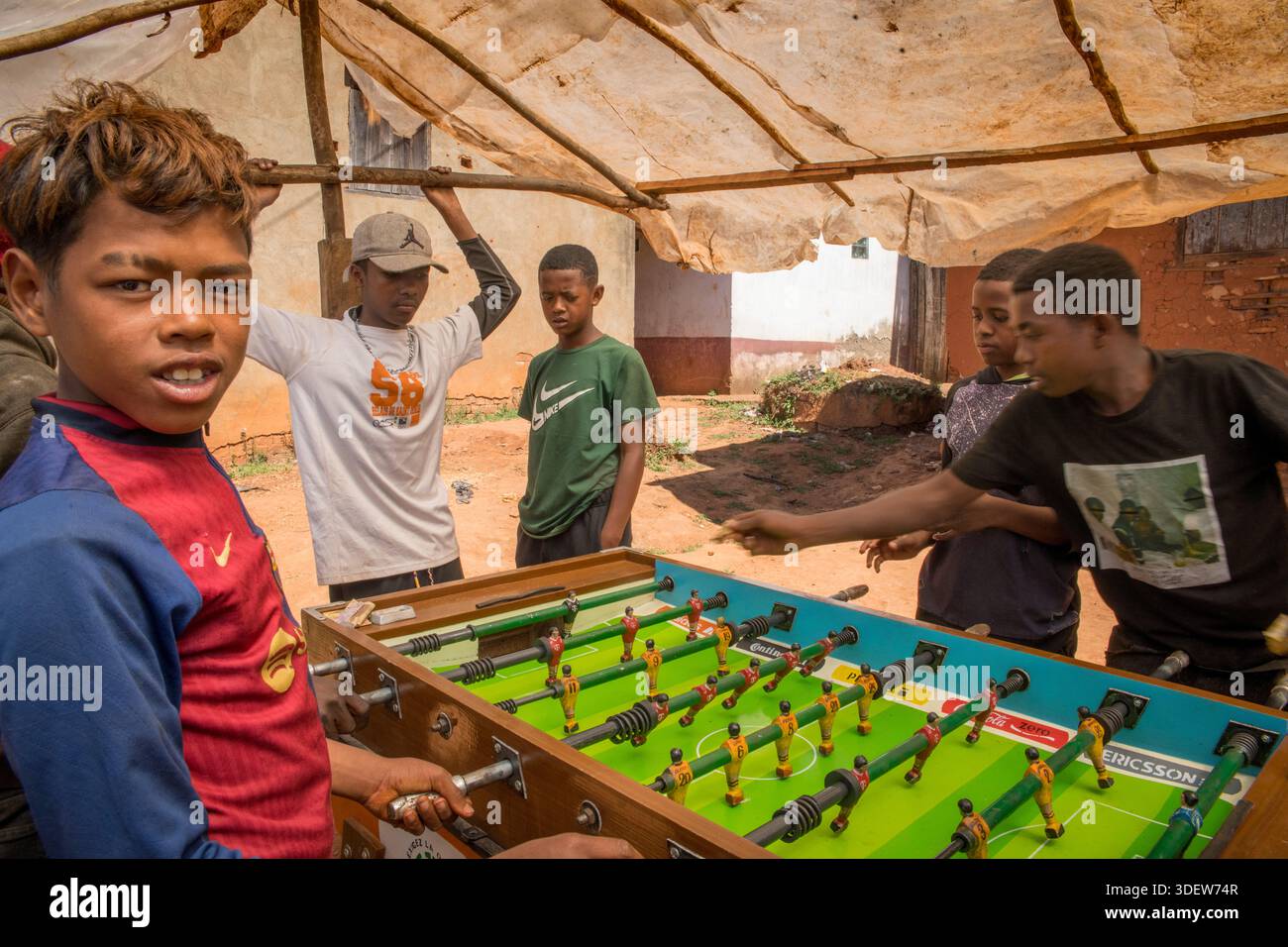 Gli adolescenti del posto si divertono con una partita informale di calcio balilla a Camp Robin, un comune rurale degli altopiani centrali del Madagascar. La scena cattura un momento di svago quotidiano e di vita della comunità nella regione di Haute Matsiatra. Foto Stock