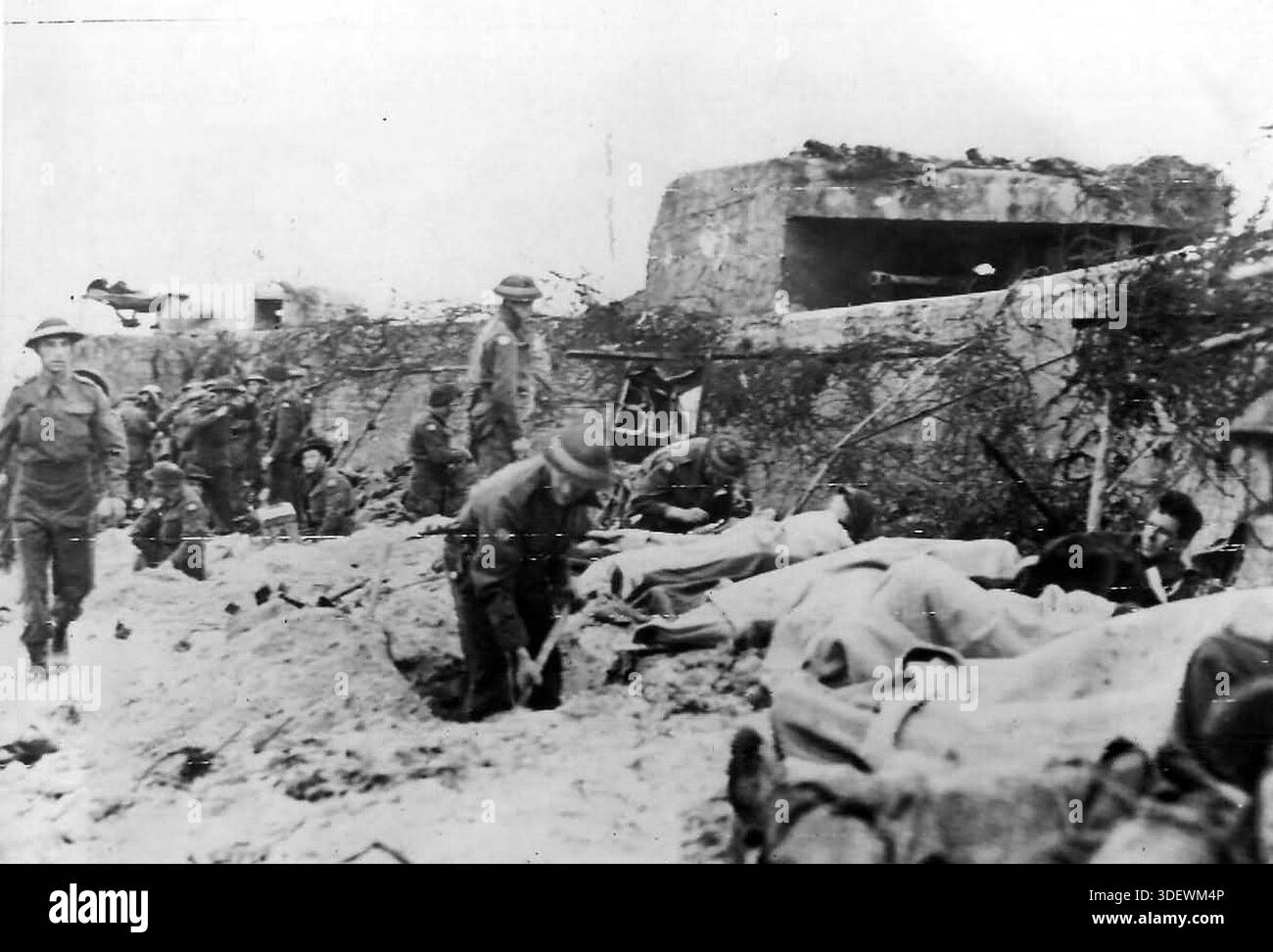 Truppe canadesi ferite sulla spiaggia di Juno il D-Day. Il 6 giugno 1944 un'enorme forza d'invasione Alllied che coinvolgeva 7000 navi e 140.000 uomini sbarcò con successo sulla costa francese e stabilì cinque teste di spiaggia. Una campagna di inganno di successo significò che gran parte della resistenza tedesca si trovava a Calais e le perdite furono relativamente poche per le dimensioni e i rischi dell'operazione. Foto Stock