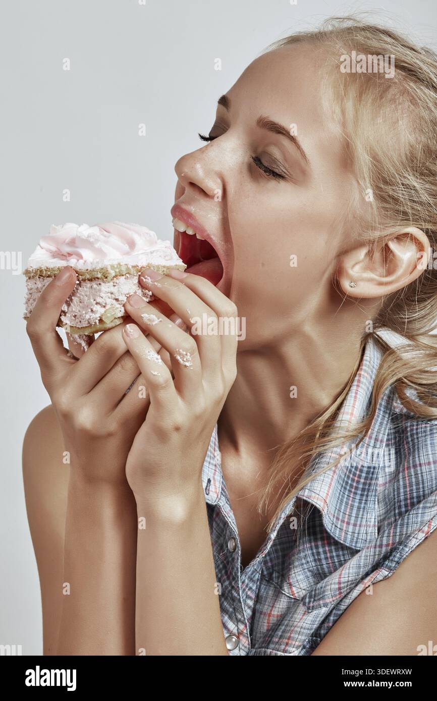 Bella ragazza divertente con pan di Spagna su sfondo bianco Foto Stock