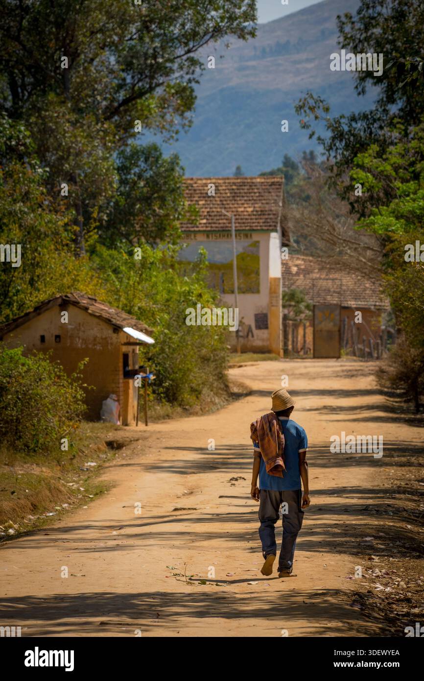 Uomo malgascio che cammina lungo una strada rurale sterrata in un villaggio alla periferia di Fianarantsoa Foto Stock