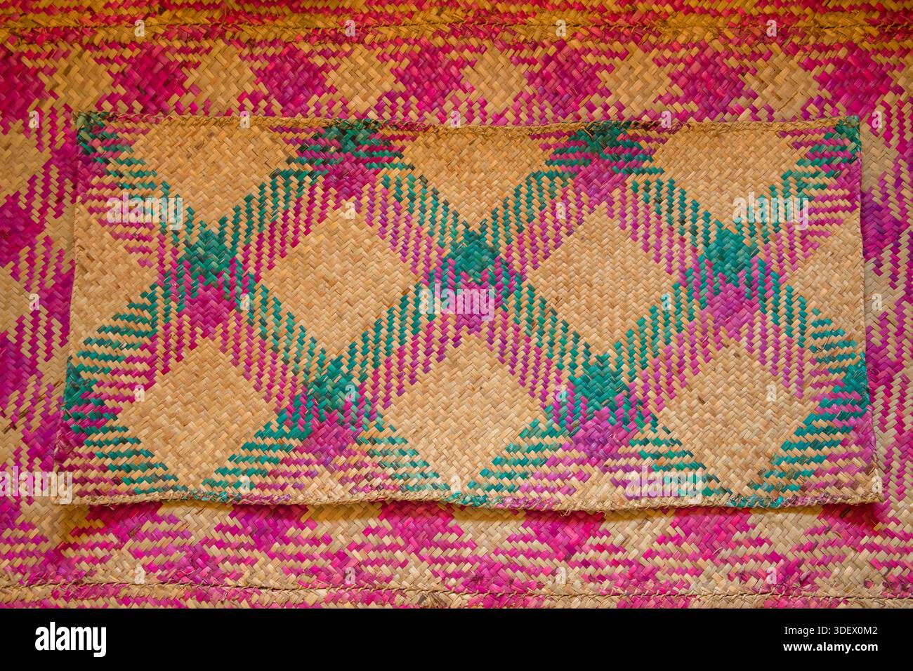 Tappetini in tessuto magenta, verde e semplice rafia color beige. Usato sul pavimento di una casa locale. Antsaharoa, villaggio alla periferia di Fianarantsoa. I tappeti intrecciati sono un elemento fondamentale della vita e della cultura malgascia, molto apprezzati nelle case tradizionali di villaggi come Antsaharoa, vicino a Fianarantsoa. L'uso di vibranti rafia magenta e beige mette in risalto le abilità artigianali del popolo Betsileo. Foto Stock