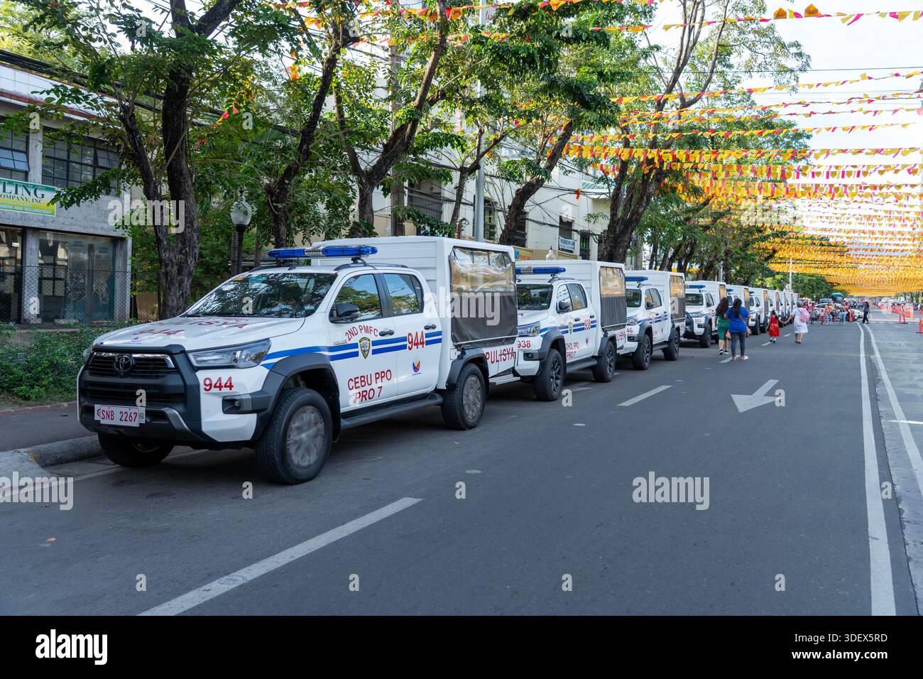 I veicoli della polizia della città di Cebu fiancheggiano una strada del festival decorata per Sinulog, che mette in evidenza i preparativi per la sicurezza e le misure di controllo della folla durante il Festi. Foto Stock