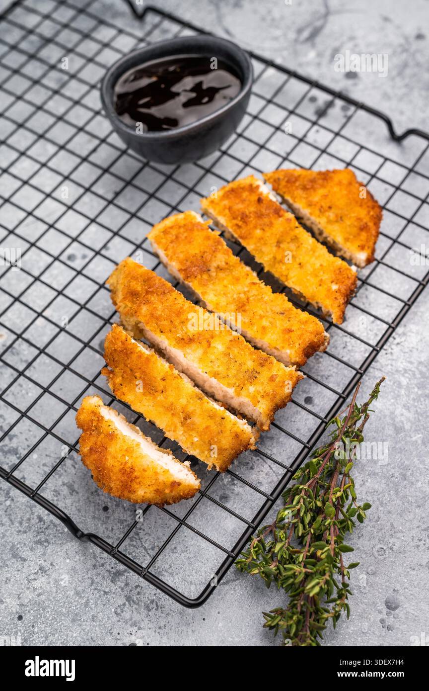 Tenero cotoletta di pollo katsu, ricoperta di pangrattato croccante e fritta alla perfezione. Ideale per un pasto soddisfacente o come condimento per il riso. sfondo grigio Foto Stock