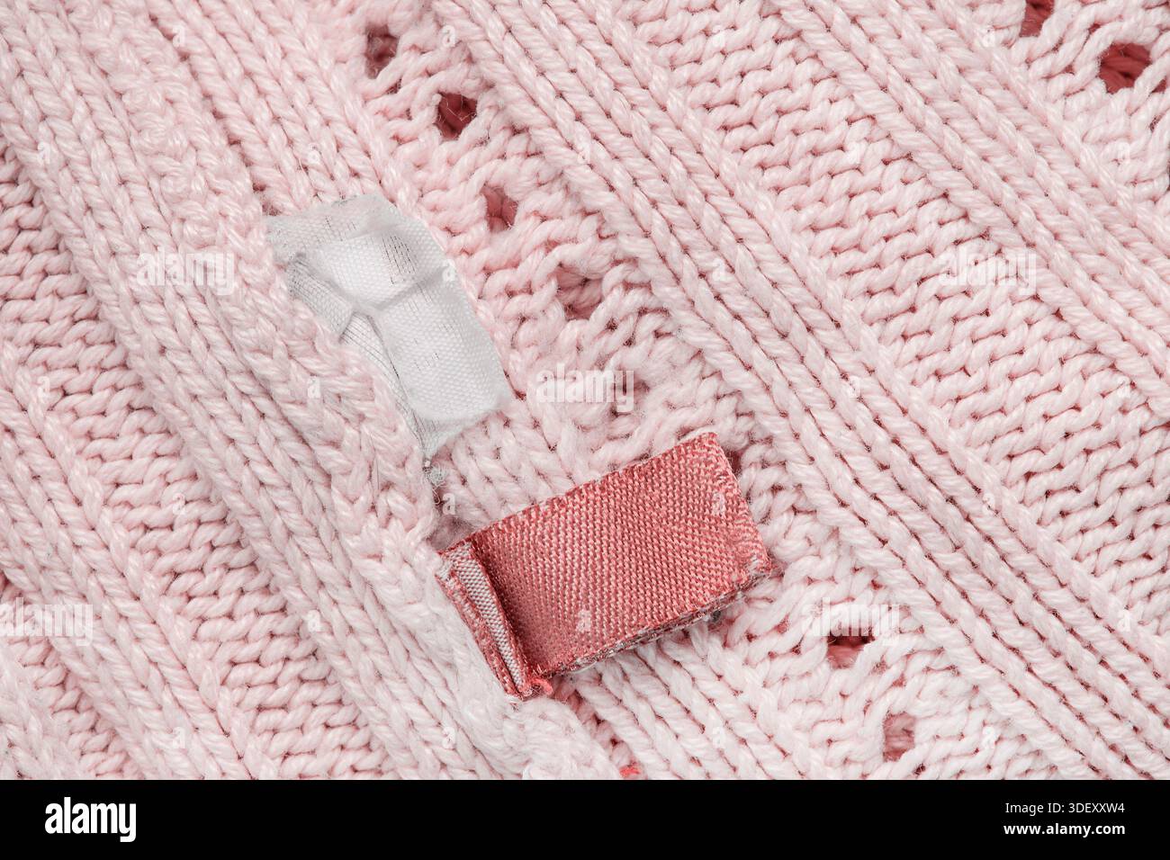 Etichette per abiti cucite sulla parte inferiore del capo in maglia rosa pastello Foto Stock
