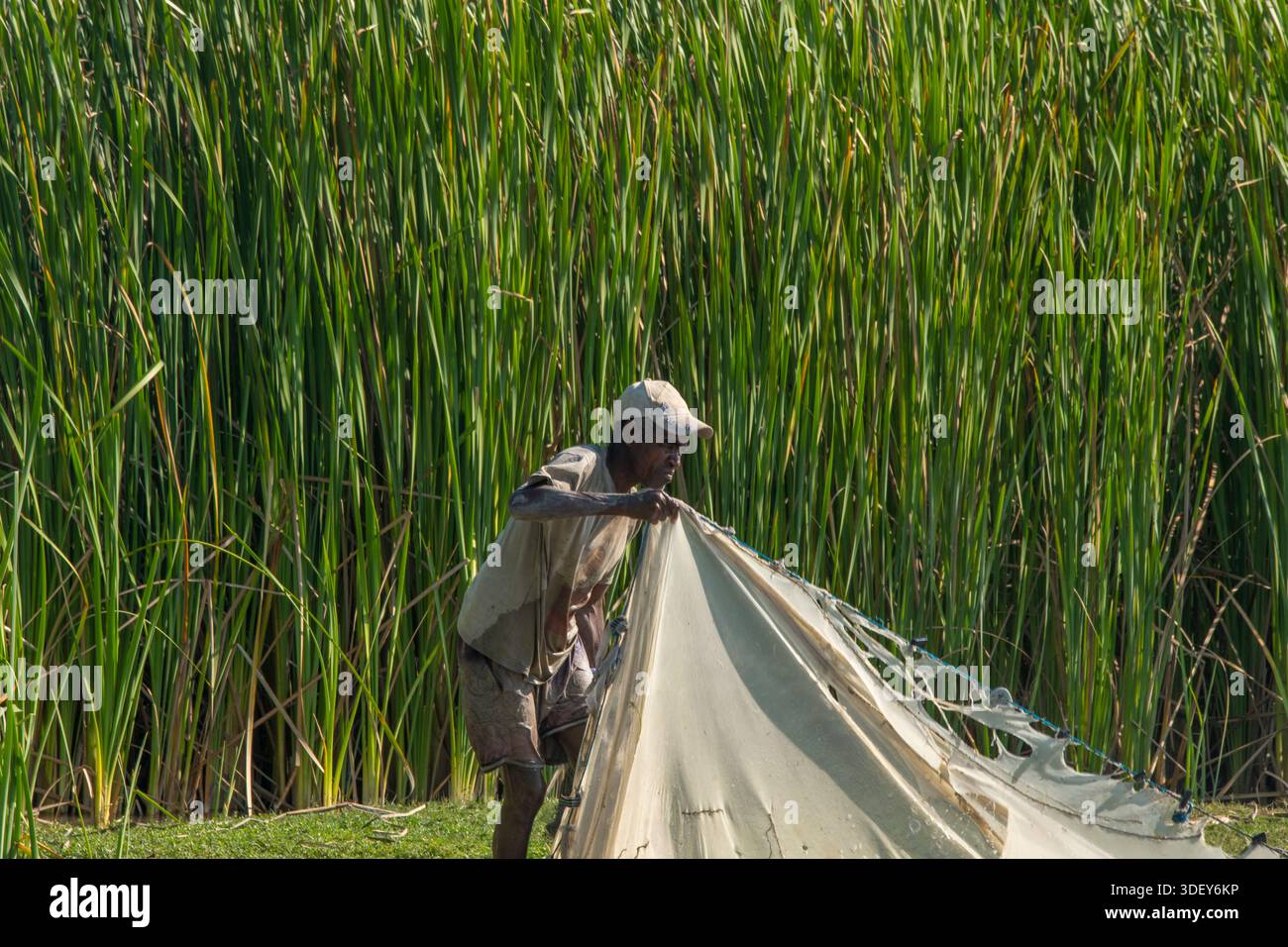 L'uomo malgascio ha portato le vele della sua canoa a cavallo nelle acque costiere poco profonde dell'entroterra di Andalambezo, Madagascar occidentale Foto Stock