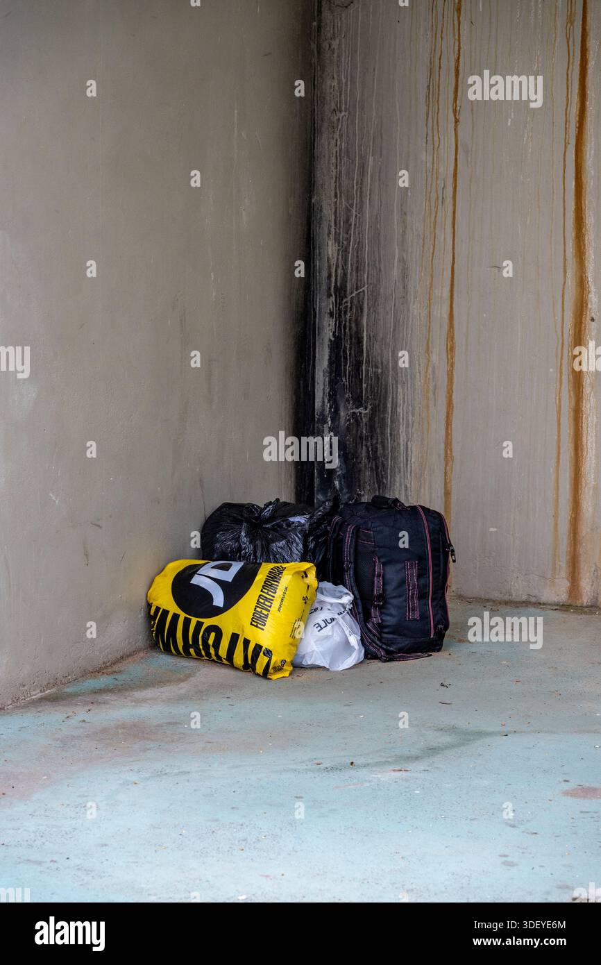 Senzatetto effetti personali in borse lasciate in un angolo tra due edifici per riparo in centro città. Foto Stock