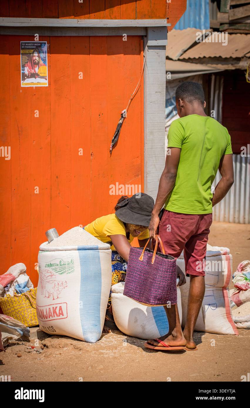 Uomo malgascio che compra riso da una donna del posto al mercato, Belo Tsiribihina, Madagascar occidentale. Foto Stock