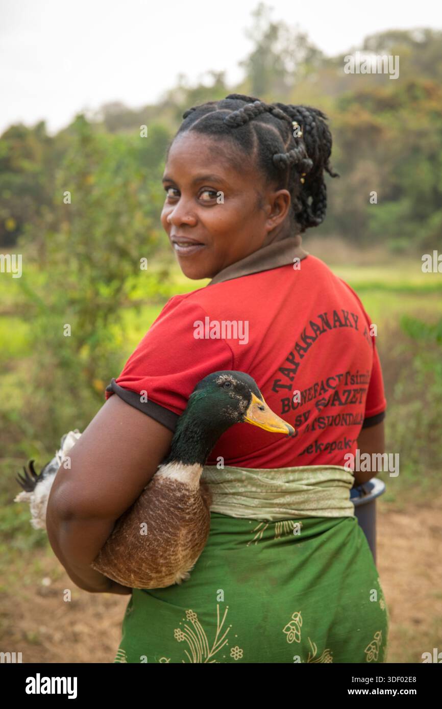 Ritratto di una donna malgascia che stringe un'anatra sotto il braccio. Bekopaka, regione di Menabe, Madagascar. L'immagine riflette l'intraprendenza delle persone malgasce che utilizzano tutte le risorse disponibili. L'anatra, agganciata saldamente, è un bene prezioso in una regione in cui la povertà è diffusa e ogni animale conta. Foto Stock
