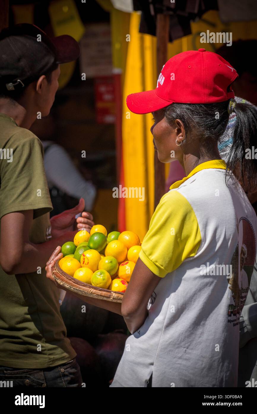 Venditore malgascio di agrumi che esporta limoni e limes al mercato, nel centro di Antananarivo, Madagascar. Ad Antananarivo, i vivaci mercati centrali sono il fulcro dei prodotti freschi, dove i venditori espongono in modo prominente una varietà di agrumi, tra cui limoni e limes. Il vivace mercato di Analakely è un punto chiave per questa attività. Foto Stock