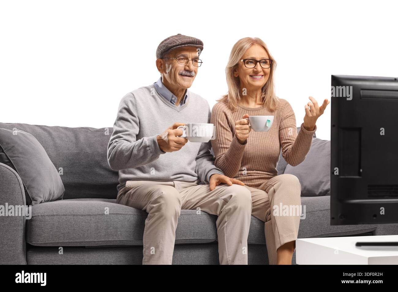 Allegra coppia matura che guarda la televisione e beve un caffè isolato su sfondo bianco Foto Stock