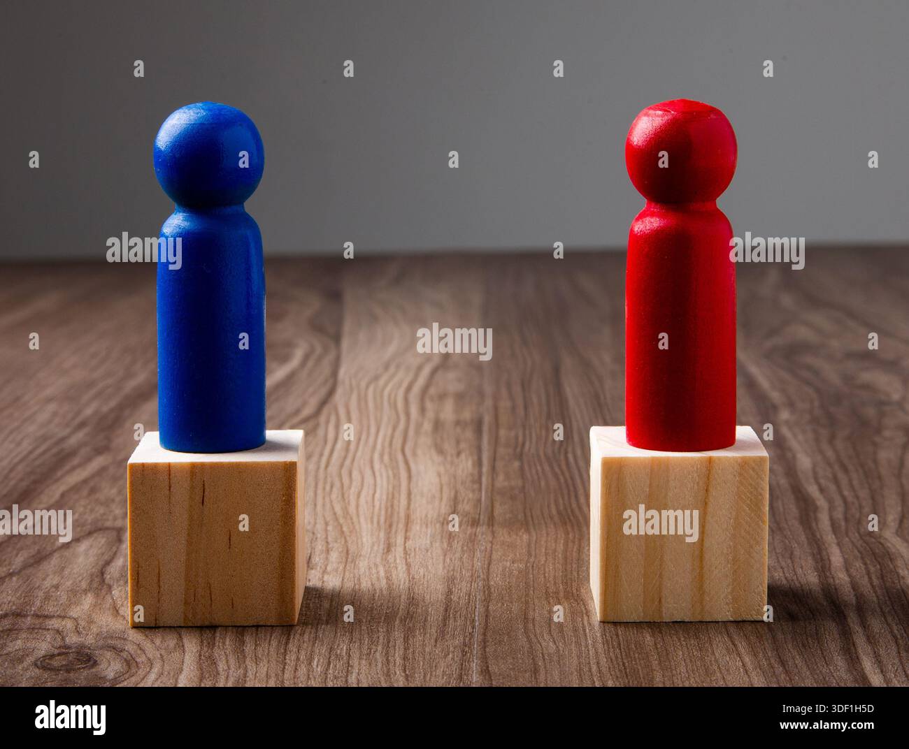 Due pedine colorate su blocchi di legno raffiguranti conflitti o competizioni Foto Stock