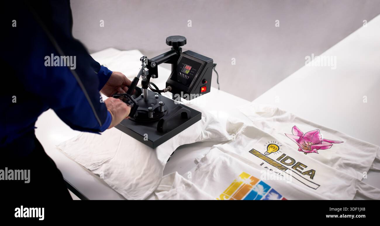 Giovane ispanico che utilizza la pressa termica per stampare il logo personalizzato della camicia. Foto Stock