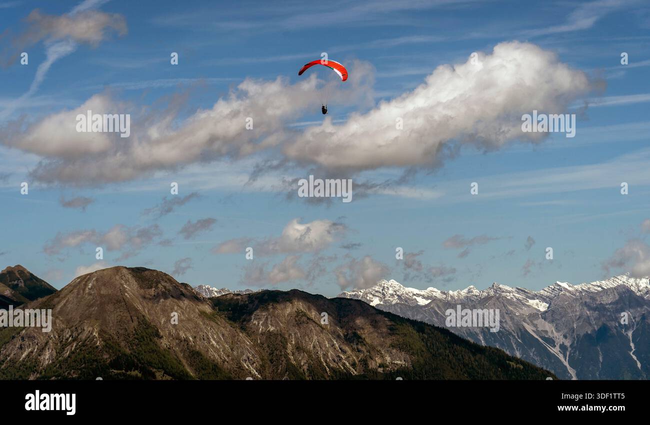Parapendio che sorvola la catena montuosa sotto il cielo blu Foto Stock