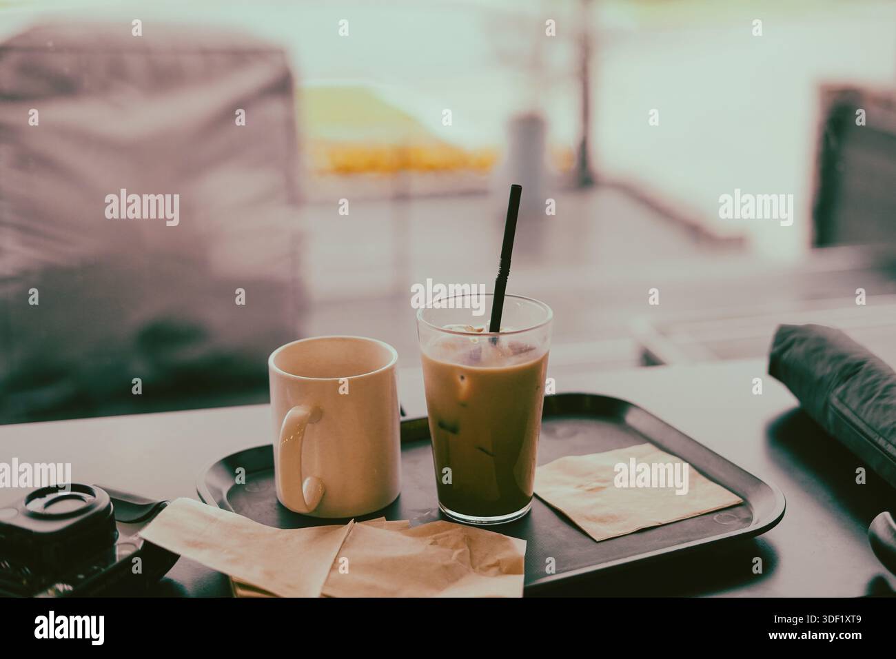 Latte ghiacciato e tazza vuota su un vassoio vicino alla finestra Foto Stock