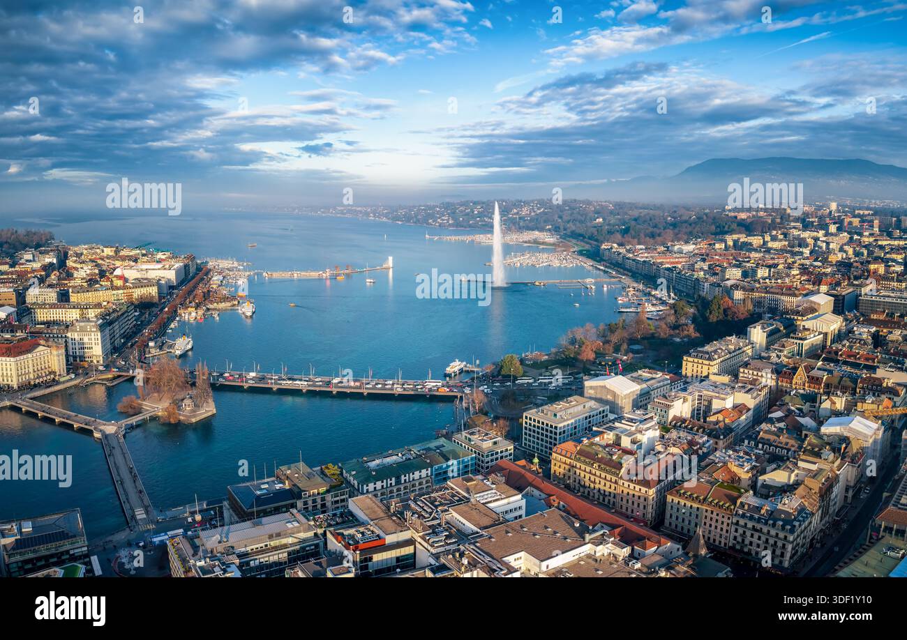Vista aerea del paesaggio urbano e del lago di Ginevra, in Svizzera, durante una soleggiata giornata invernale con nebbia, nuvole e sole Foto Stock
