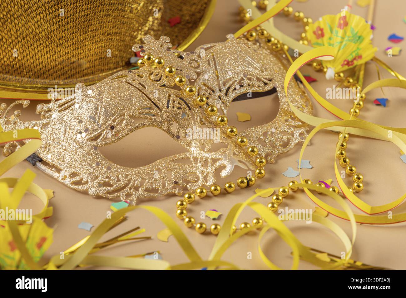 Maschera dorata con perle circondata da decorazioni carnevalesche Foto Stock