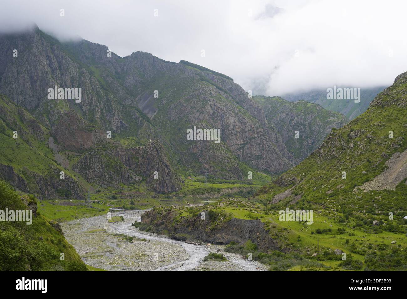 Possenti montagne con copertura nuvolosa, un fiume attraversa la verde valle con rocce e vegetazione, il fiume Tergi, Terek, Darial Gorge, Dariel Gorge, Ka Foto Stock
