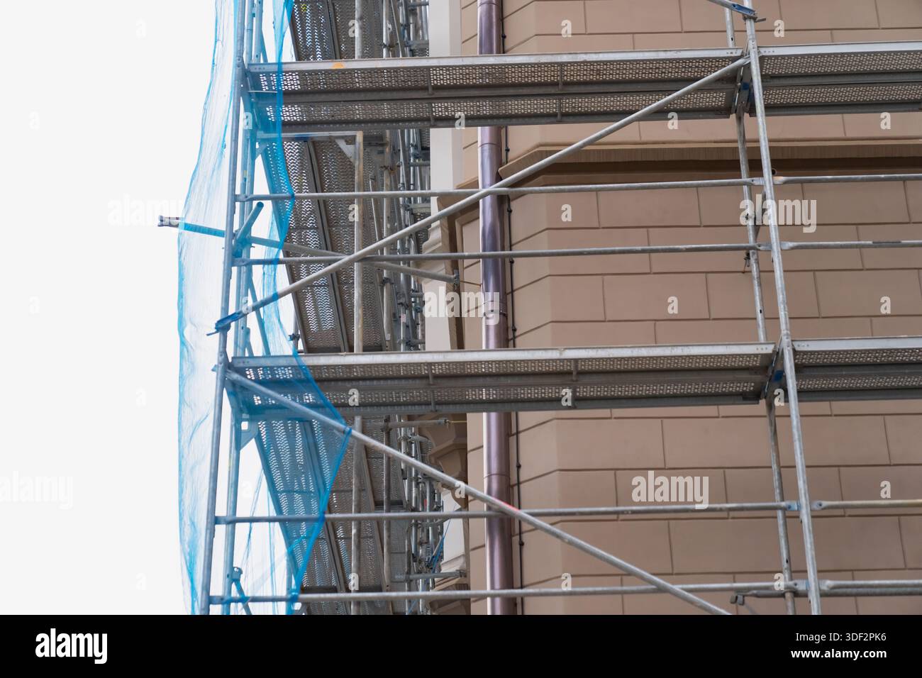 Ponteggi in metallo per costruzioni con rete di sicurezza installata lungo la facciata dell'edificio che mostra i lavori di ristrutturazione piattaforme temporanee e sistema di supporto strutturale Foto Stock