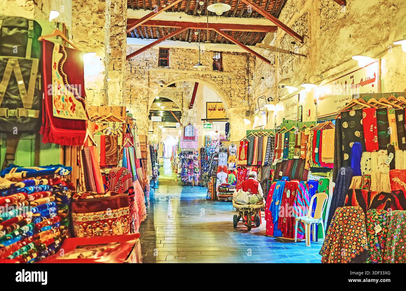 Ampia gamma di tessuti colorati, tappeti e arazzi nel vicolo coperto del Souq Waqif - tradizionale mercato orientale a Doha, Qatar Foto Stock