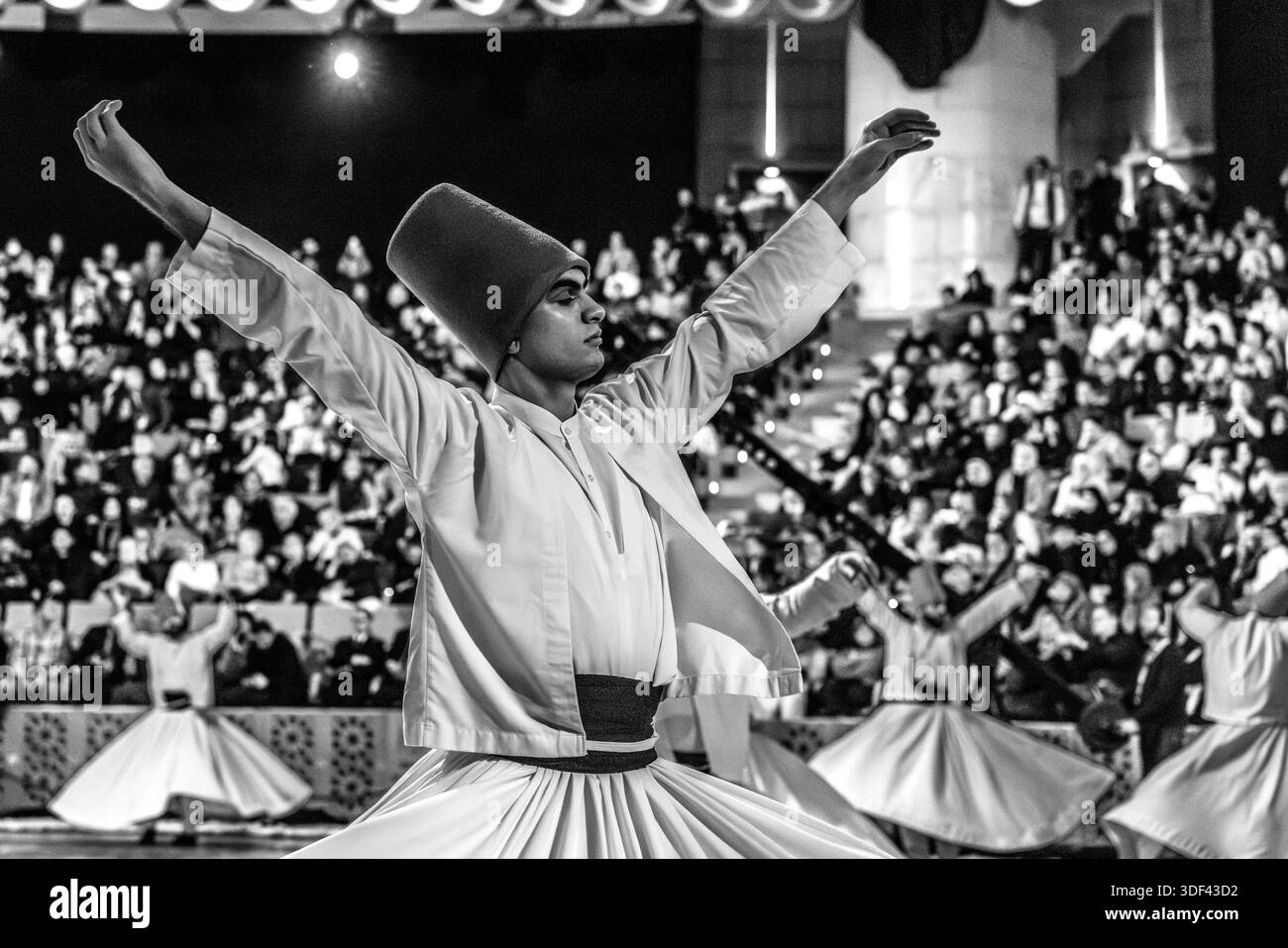 La cerimonia Şeb-i Arus al Mevlana Kültür Merkezi a Karatay, Konya, Turchia, un luogo che può ospitare 3.000 persone, mostra dei dervisci durante la danza rituale Sema. La mano destra punta verso l'alto, ricevendo la benedizione di Dio. La mano sinistra punta verso il basso, passandola alla terra. I dervisci girano in senso antiorario, simbolicamente contro l'ego. Il piede destro rimane fisso mentre il piede sinistro guida la rotazione. Şeb-i Arus è la festa annuale che segna l'anniversario della morte (17 dicembre) del poeta mistico Rumi (Jalāl ad-Dīn ar-Rūmī, 1207–1273), fondatore dell'ordine Mevlevi, celebrato come Foto Stock