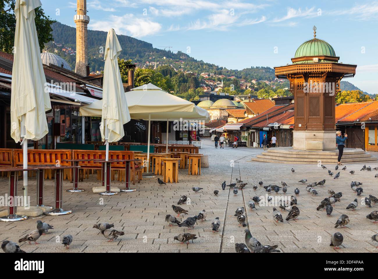 Sarajevo, Bosnia ed Erzegovina - 15 agosto 2022: I piccioni si riuniscono intorno alla fontana di legno di Sebilj in piazza Bascarsija nella città vecchia di Sarajevo con i suoi caffè Foto Stock