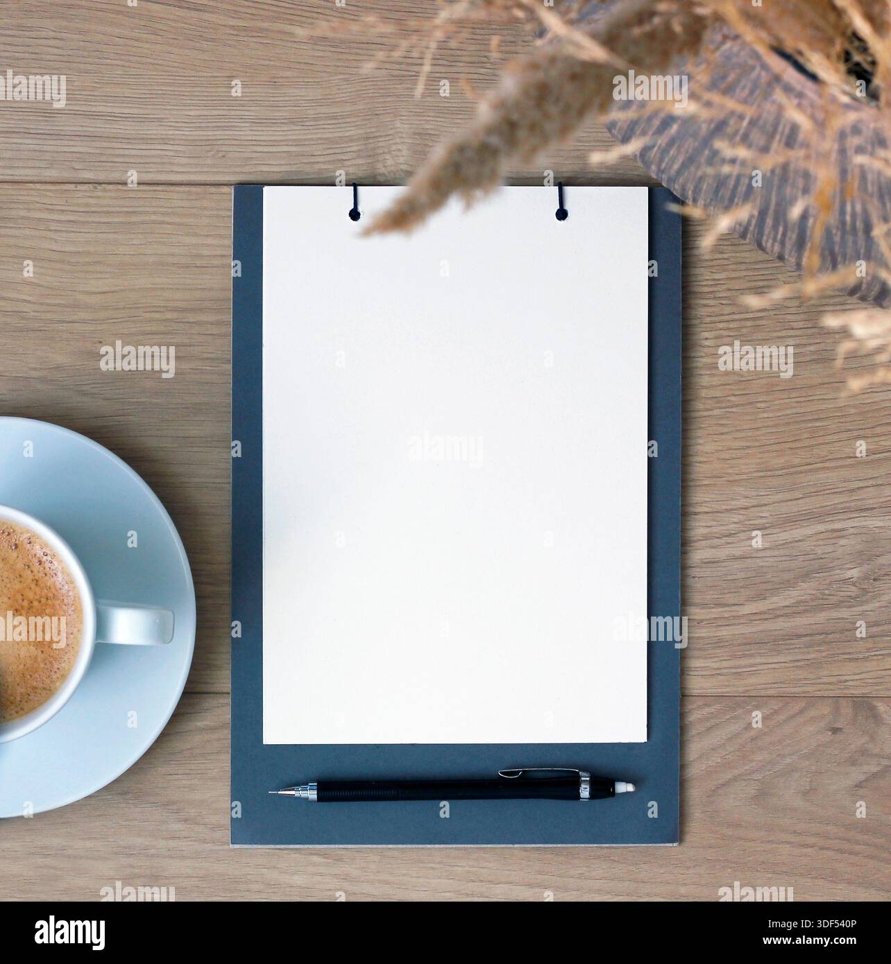 Disposizione piatta di una pagina vuota del notebook con penna e caffè su un tavolo di legno, concetto minimo di spazio di lavoro per la pianificazione, elenchi di attività, obiettivi, risoluzioni, note Foto Stock