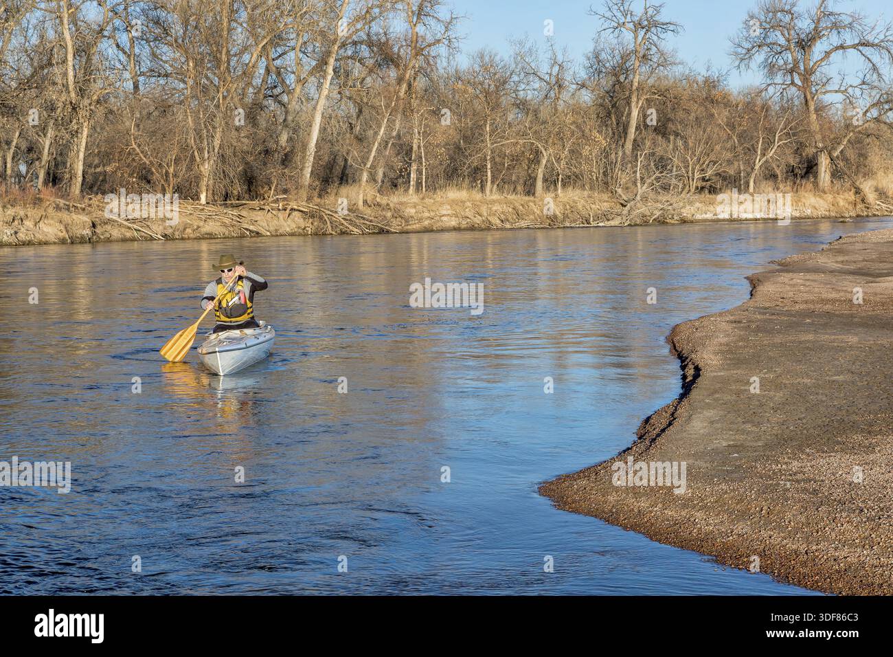 Paddler senior in una canoa da spedizione sul fiume South Platte nel Colorado orientale, scenario invernale senza neve Foto Stock
