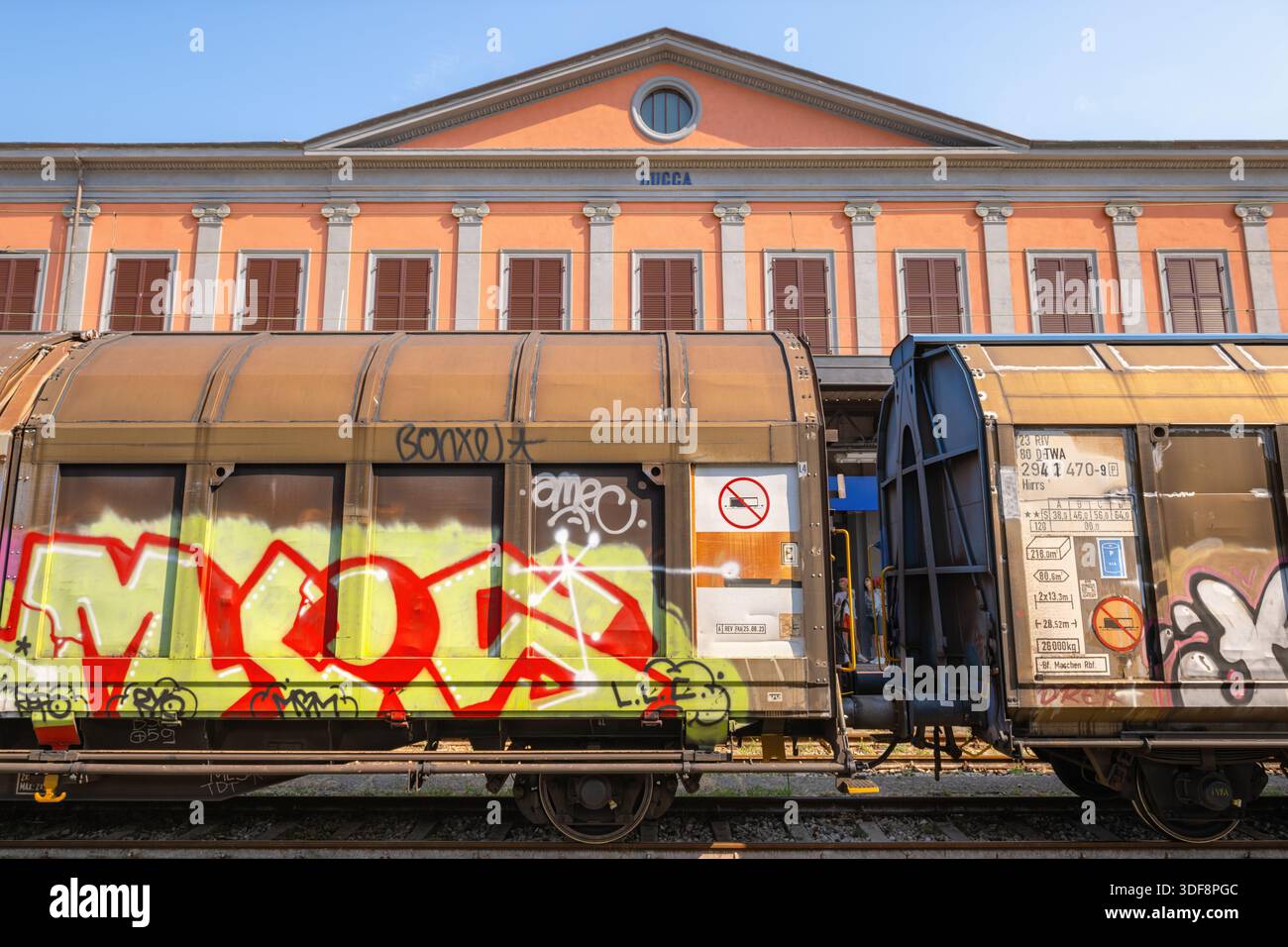 Immagine scattata nella stazione ferroviaria della città di Lucca, Italia, che mostra un treno merci coperto di graffiti e arte urbana. Foto Stock