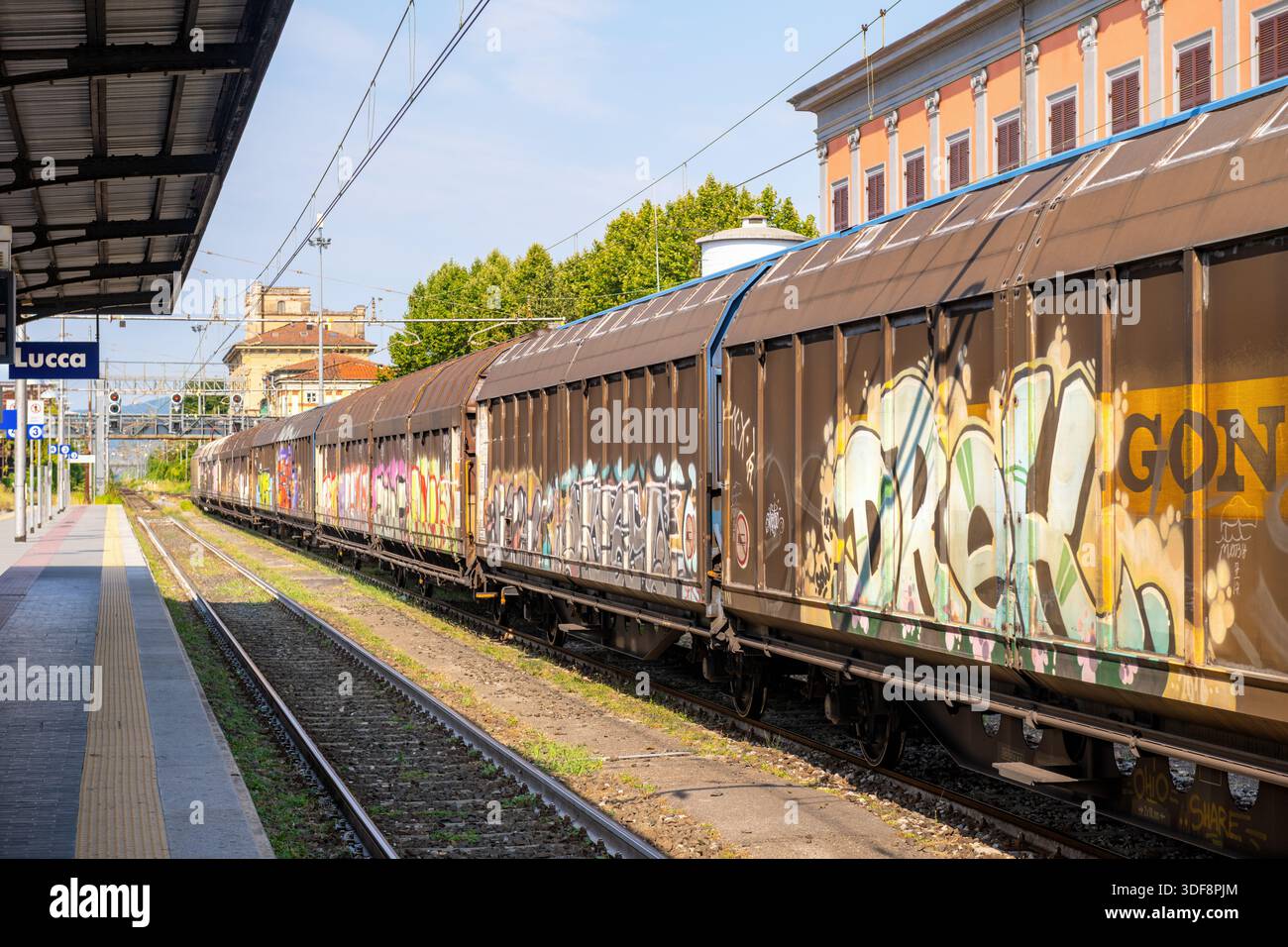 Immagine scattata nella stazione ferroviaria della città di Lucca, Italia, che mostra un treno merci coperto di graffiti e arte urbana. Foto Stock