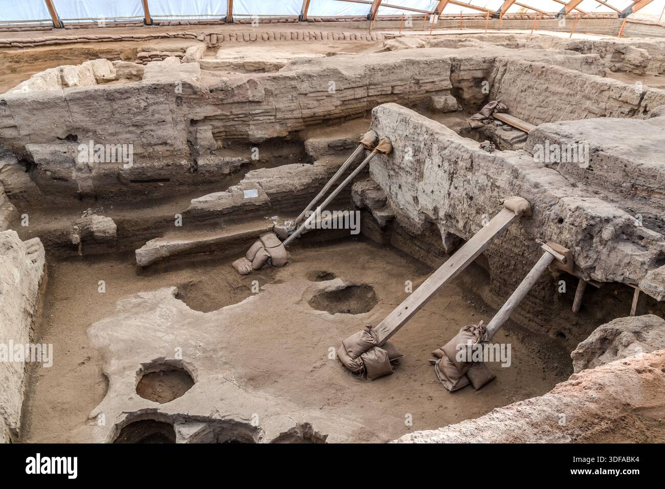 Supporti diagonali in legno sostengono le mura scavate di una casa di Çatalhöyük vicino a Küçükköy, in Turchia, sopra due fosse rotonde affondate nel pavimento in argilla della casa. Fosse circolari come queste erano tipicamente utilizzate dagli abitanti neolitici di Çatalhöyük, uno degli insediamenti neolitici più famosi al mondo, come contenitori di stoccaggio. Foto Stock