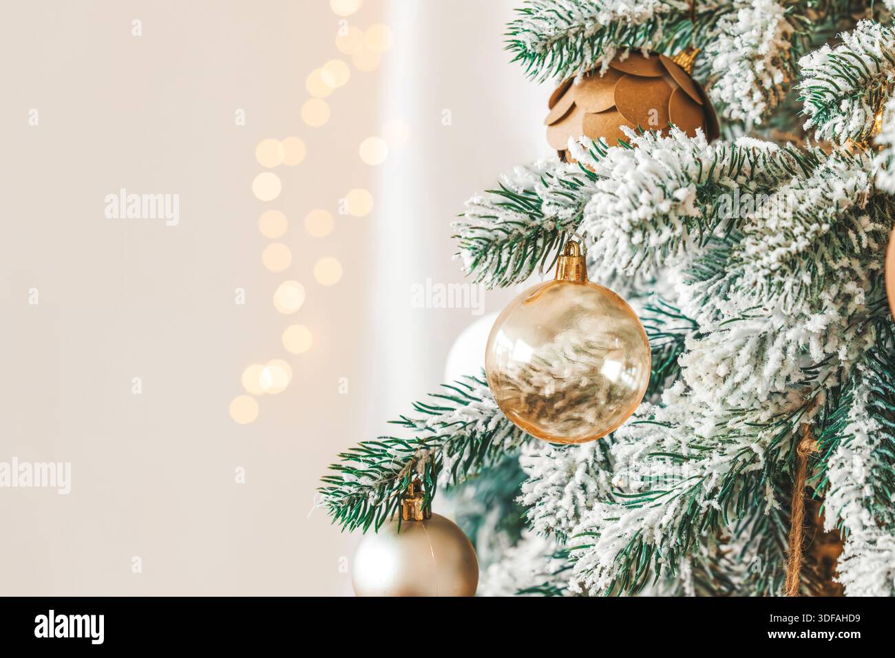 Rami di alberi di Natale smerigliati e innevati decorati con palline di vetro ornate e calde luci dorate con copia dello sfondo. Vittoria magica e accogliente Foto Stock