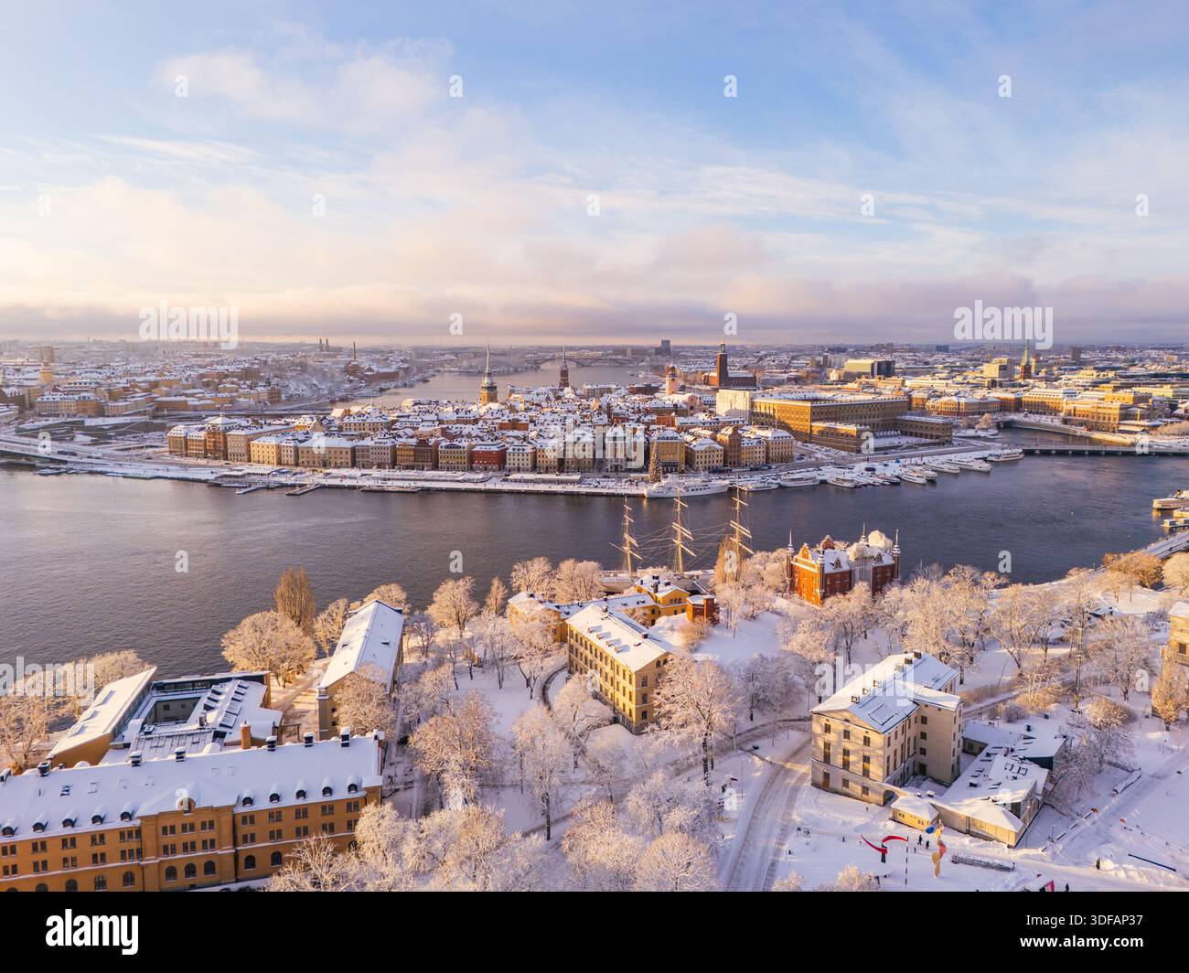 Una vista aerea con drone dell'isola di Skeppsholmen coperta di neve che guarda verso la storica città vecchia di Gamla Stan in inverno a Stoccolma, Svezia. Foto Stock
