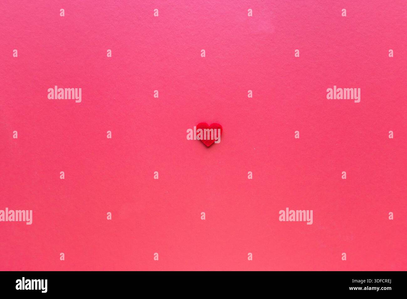 Cuore rosso singolo su sfondo rosa con spazio per le copie, concetto romantico minimale per l'amore, San Valentino e temi di relazione. Foto Stock