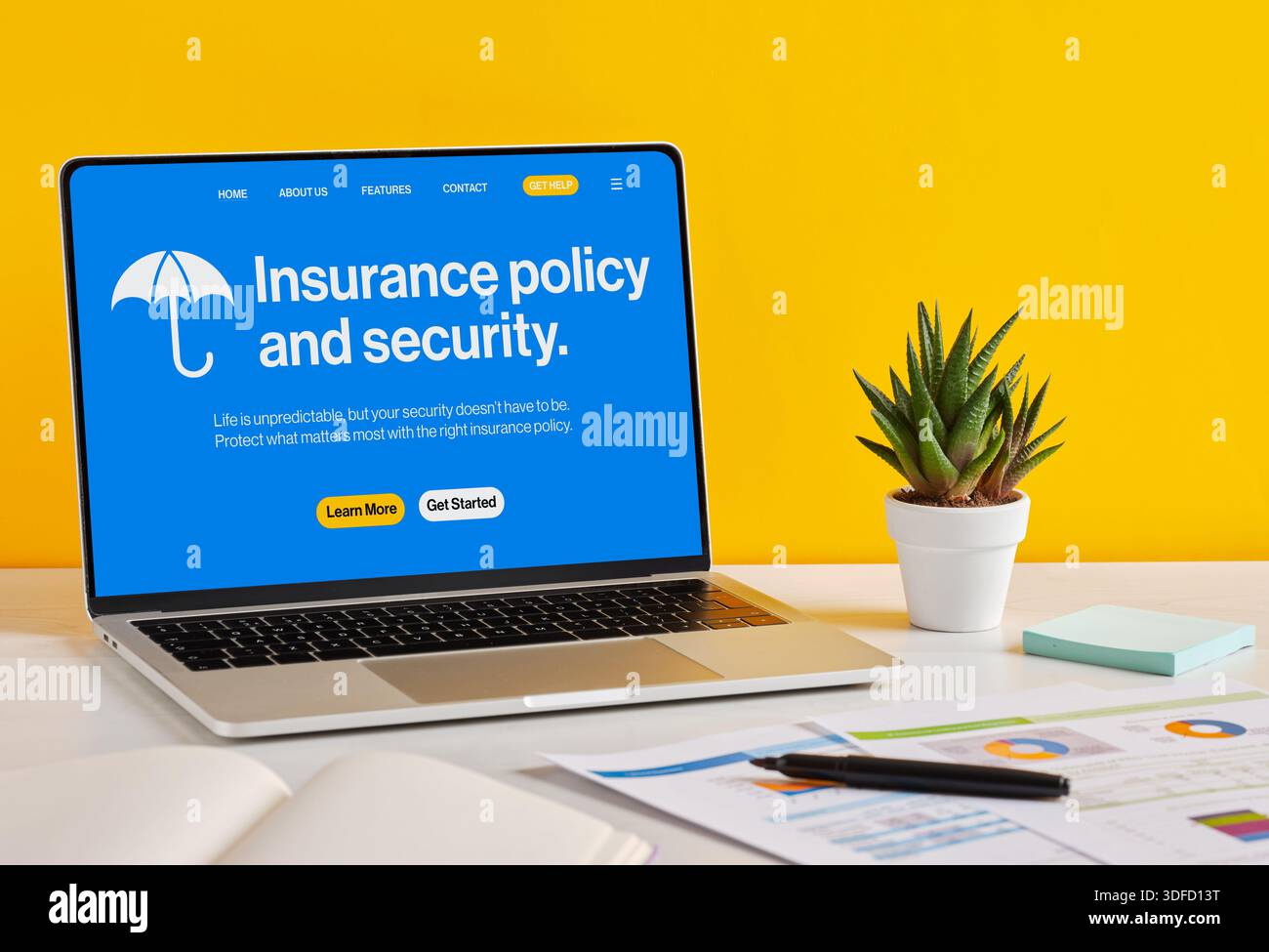 Laptop con polizza assicurativa e sito Web di sicurezza sulla scrivania con documenti, penna e impianto in vaso su sfondo giallo Foto Stock