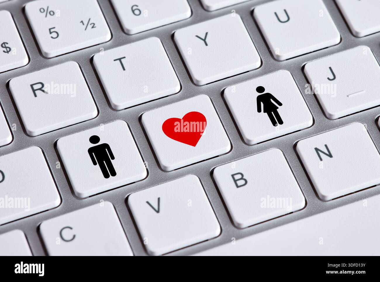 Il concetto di incontri online e amore è illustrato da un cuore rosso tra icone uomo e donna sui tasti della tastiera Foto Stock