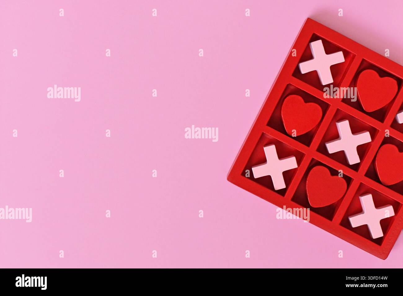 Gioco di cuore a tema San Valentino con cuori rossi e rosa e X in una scatola rossa su sfondo rosa con spazio per copiare Foto Stock
