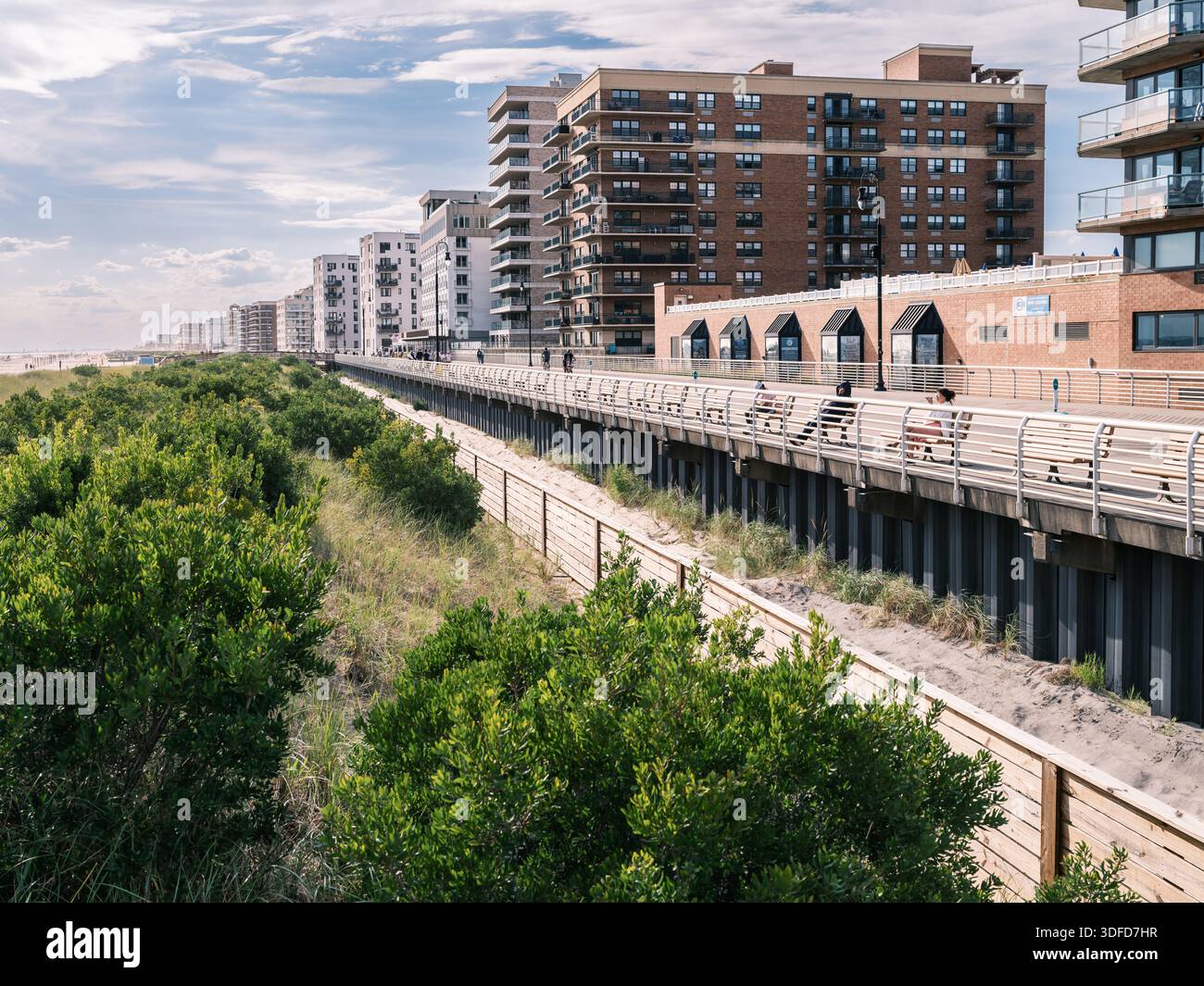 Ammira la passerella di Long Beach a New York, con condomini fronte oceano, dune e pedoni nelle giornate limpide. Foto Stock