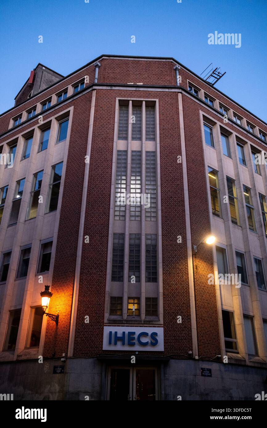 Vista architettonica dell'edificio della scuola di comunicazione IHECS illuminato al crepuscolo con lampioni e finestre che si illuminano a Bruxelles capitale in B. Foto Stock