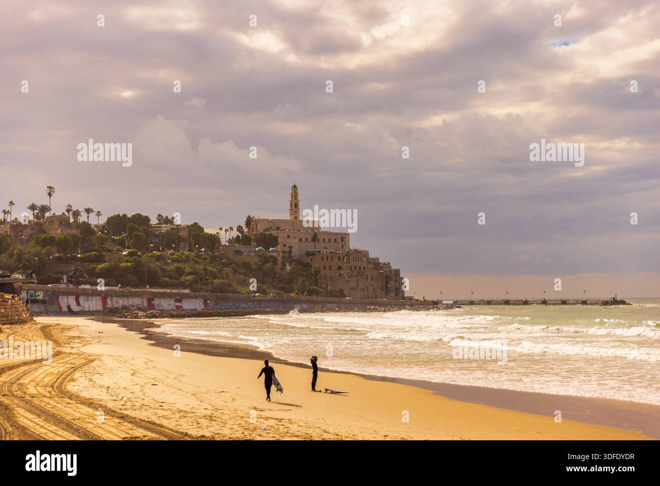 Silhouette da surfista sulla spiaggia di Tel Aviv con skyline di Jaffa silhouette di due surfisti sulla spiaggia di Tel Aviv con lo storico skyline di Jaffa nel Foto Stock