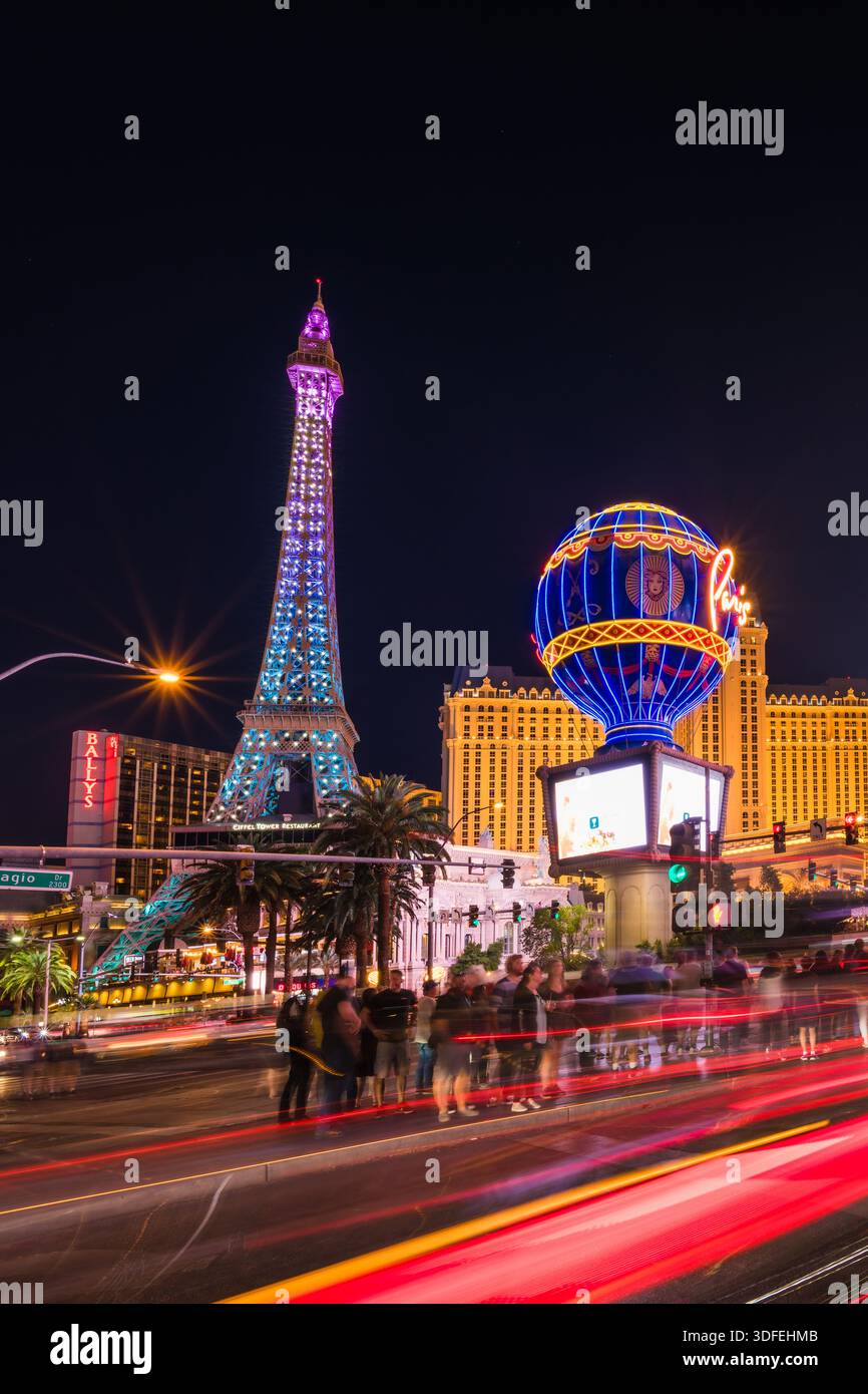 La vista della replica illuminata della Torre Eiffel e del globo luminoso si staglia in mezzo a strisce di luce sfocate nella vivace scena notturna di Las Vegas, Nevad Foto Stock