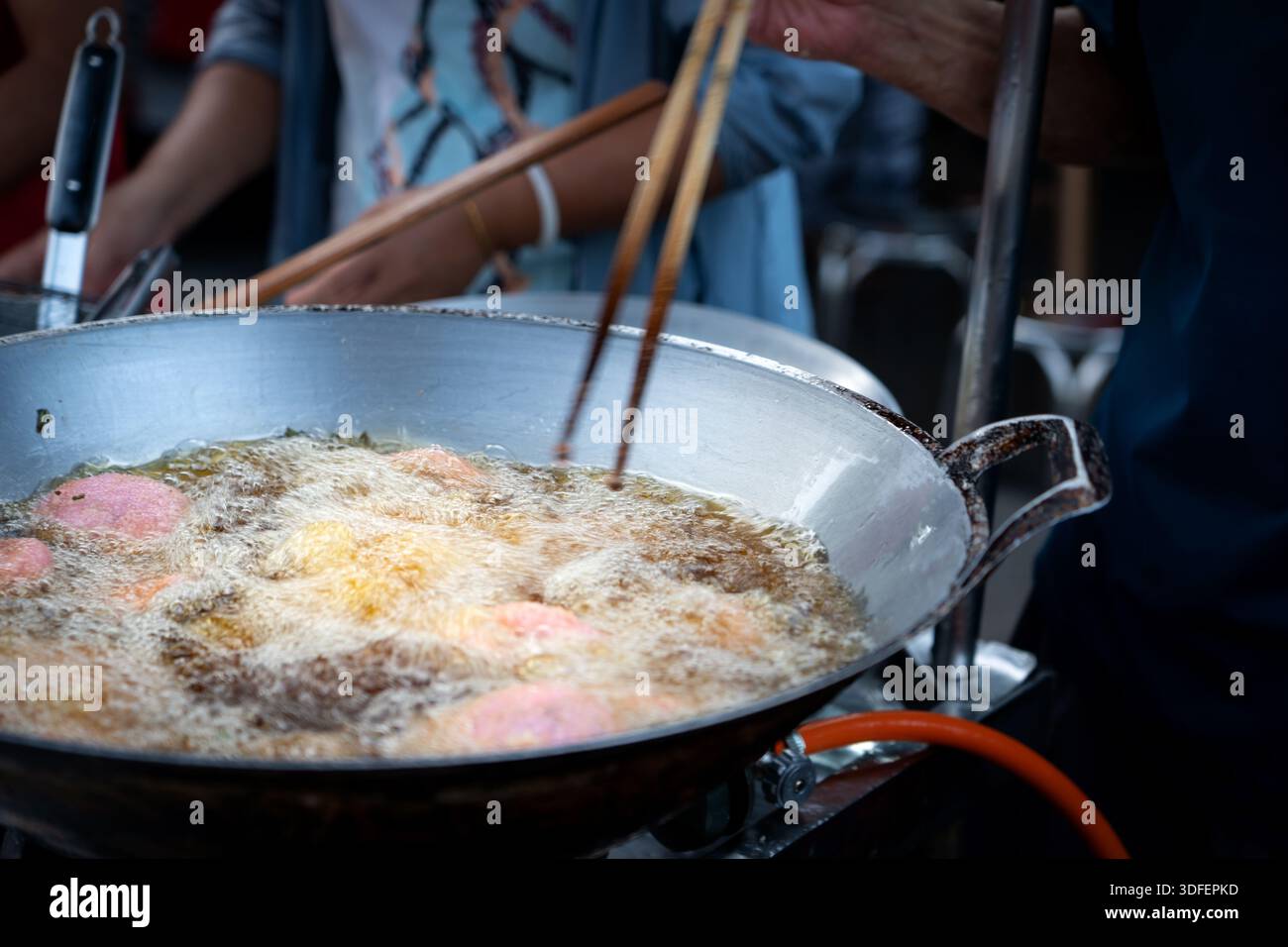 Primo piano del tofu fritto in profondità in un wok con molto olio. Cibo fritto in un wok. Il processo di cottura dello sfondo di tofu fritto. Foto Stock